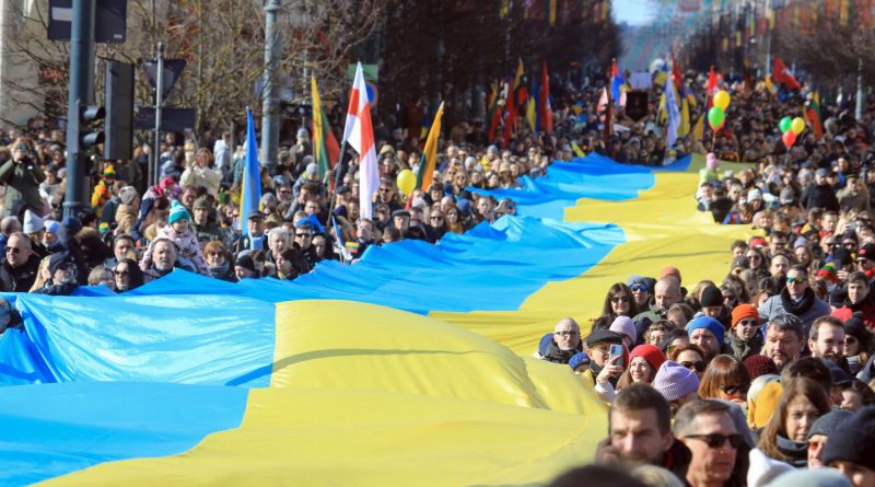 la gente camina con una bandera ucraniana gigante de muchos metros de largo para protestar contra la invasion rusa de ucrania durante una celebracion de la independencia de lituania